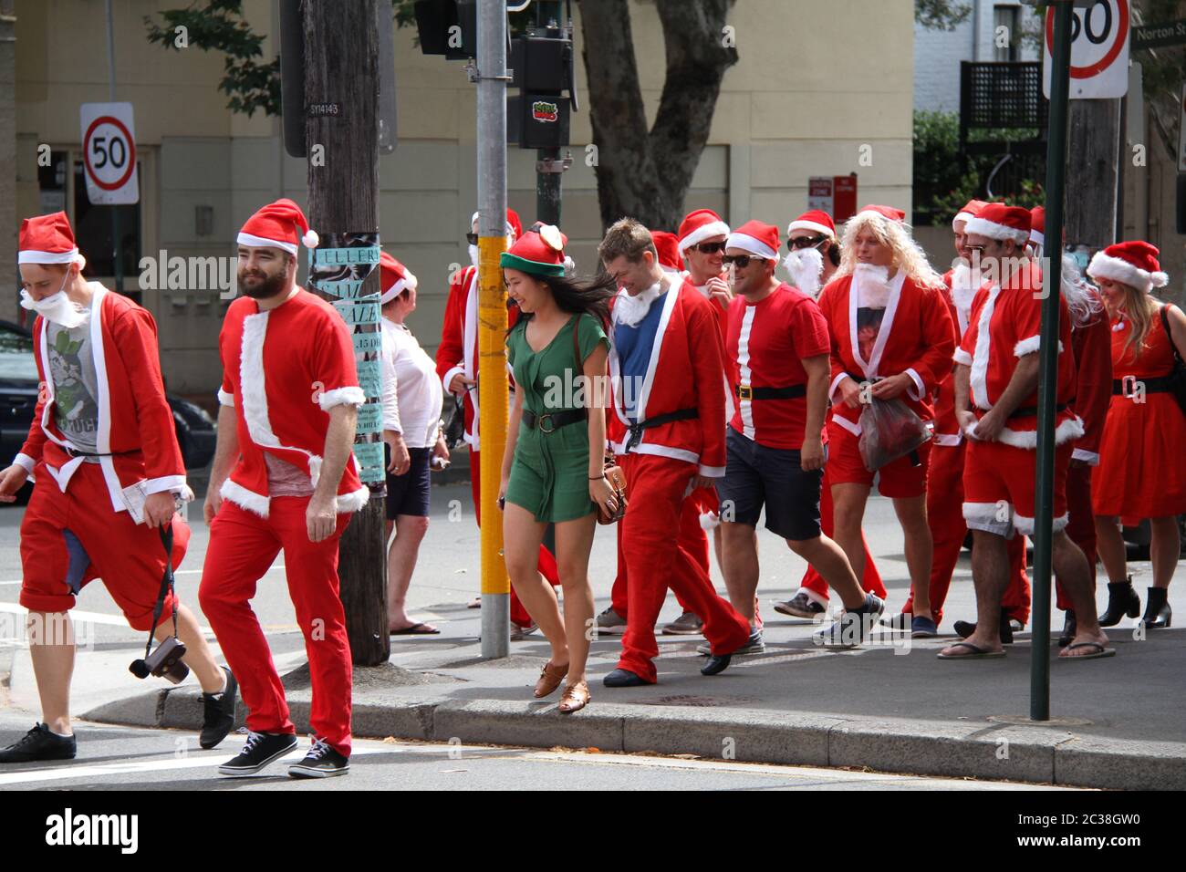 Les personnes vêtues du Père Noël prenant part au SantaCon de Sydney traversent la rue Crown Street à Surry Hills. Banque D'Images