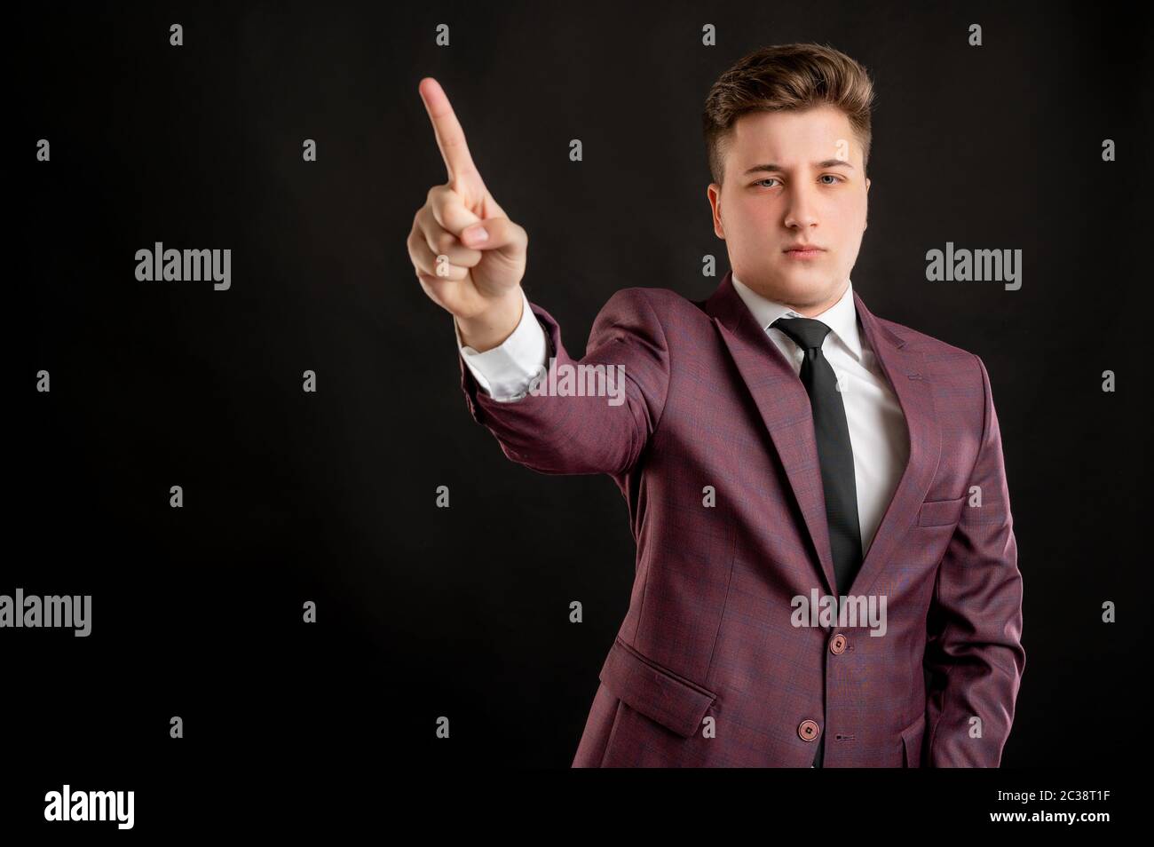 Étudiant de droit avec des cheveux blonds vêtus de blouson bordeaux, chemise  blanche et cravate noire montrant non avec son doigt posant sur un fond  noir isolé avec Photo Stock - Alamy