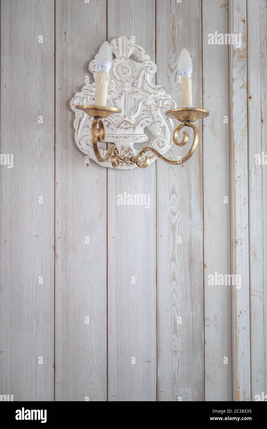 lampe à incandescence vintage avec chandeliers en fer doré suspendus sur un mur en bois peint en blanc dans la pièce Banque D'Images