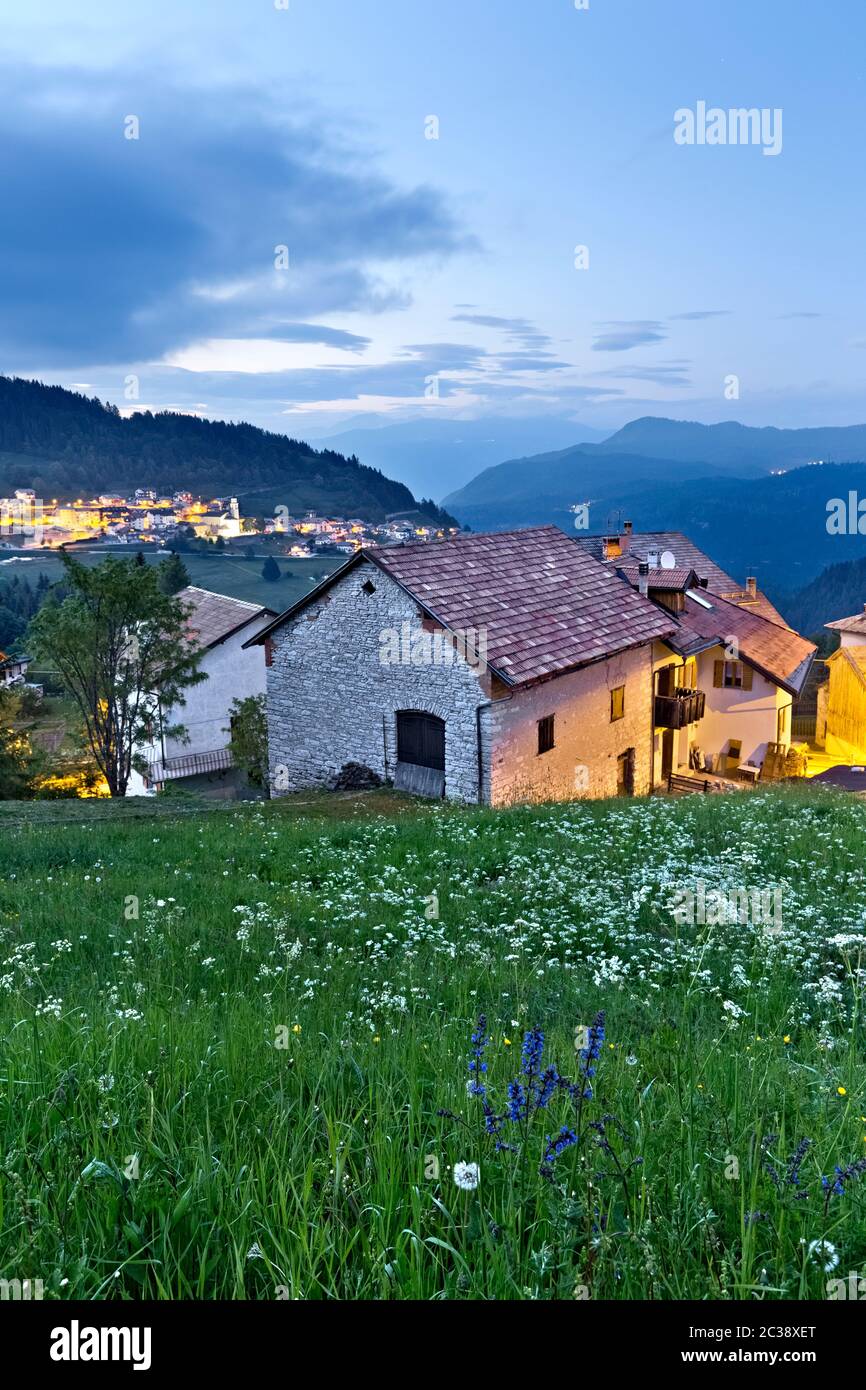 La nuit tombe au village de Perpruneri sur l'Alpe Cimbra. En arrière-plan le village de San Sebastiano. Folgaria, Trentin, Italie. Banque D'Images