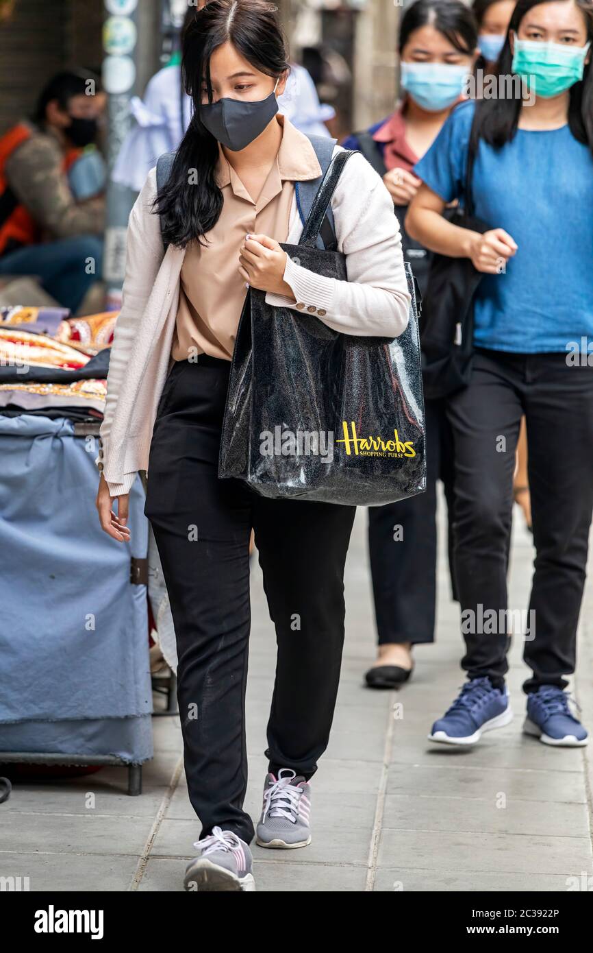 Fille portant un masque de marche avec sac de shopping pendant la pandémie Covid 19, Bangkok, Thaïlande Banque D'Images