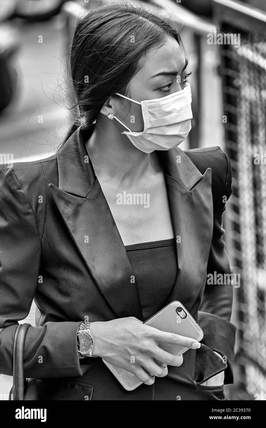 Fille avec masque et téléphone portable pendant la pandémie Covid 19, Bangkok, Thaïlande Banque D'Images