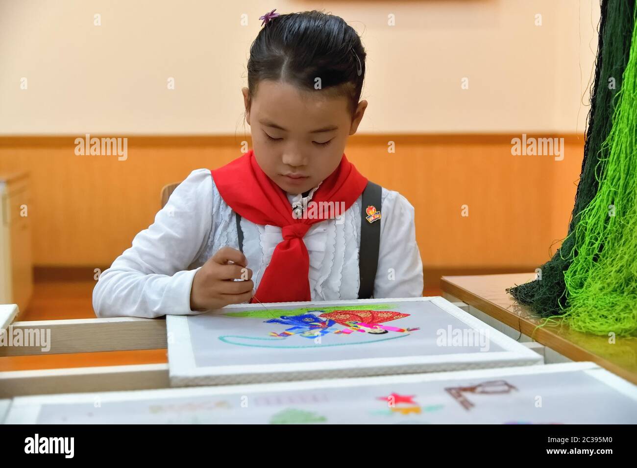 Pyongyang, Corée du Nord - 2 mai 2019 : une jeune fille pionnière coréenne broderer une photo au Palais de Pyongyang des écoliers Banque D'Images