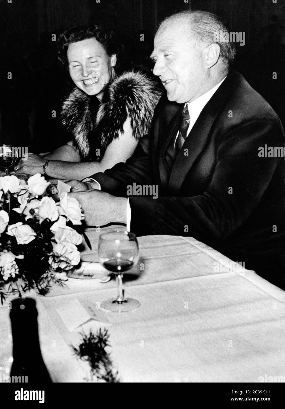Le prix Nobel et physicien Werner Karl Heisenberg souriant lors d'une conversation à une fête. Une jeune femme s'assoit à côté de lui et sourit aussi. Photo non datée, vers 1954. Banque D'Images