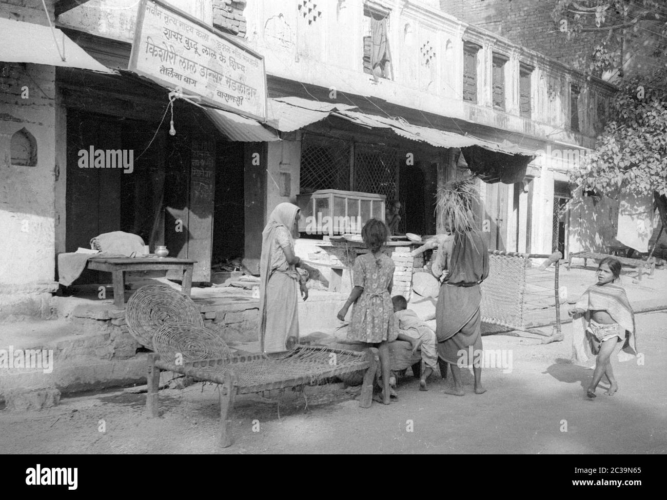 Une femme vend des tapis et des lits de paille à l'extérieur de son magasin dans la ville indienne de Benares. Banque D'Images