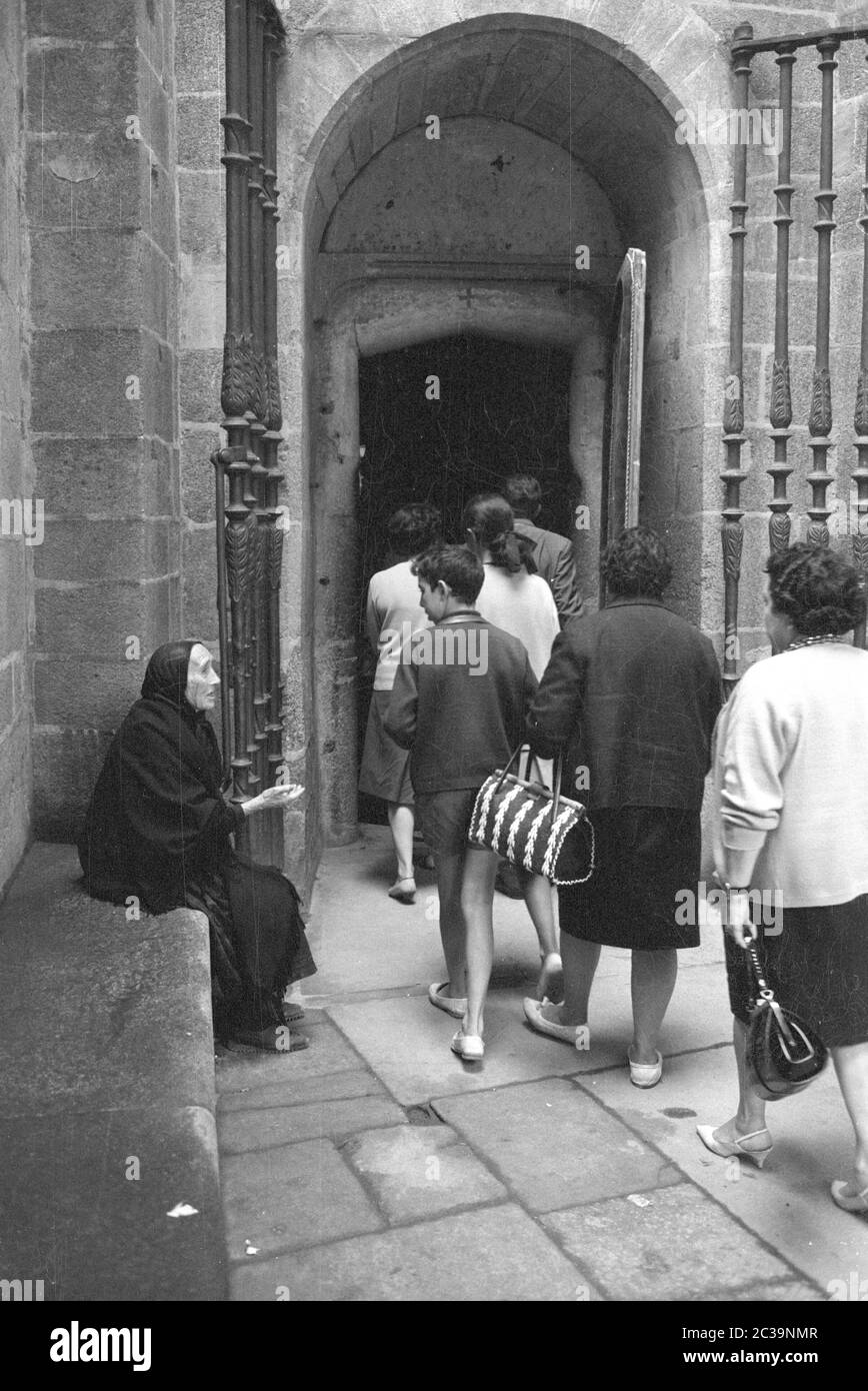 Mendiant femme et touristes à l'entrée d'une église à Madrid. Banque D'Images