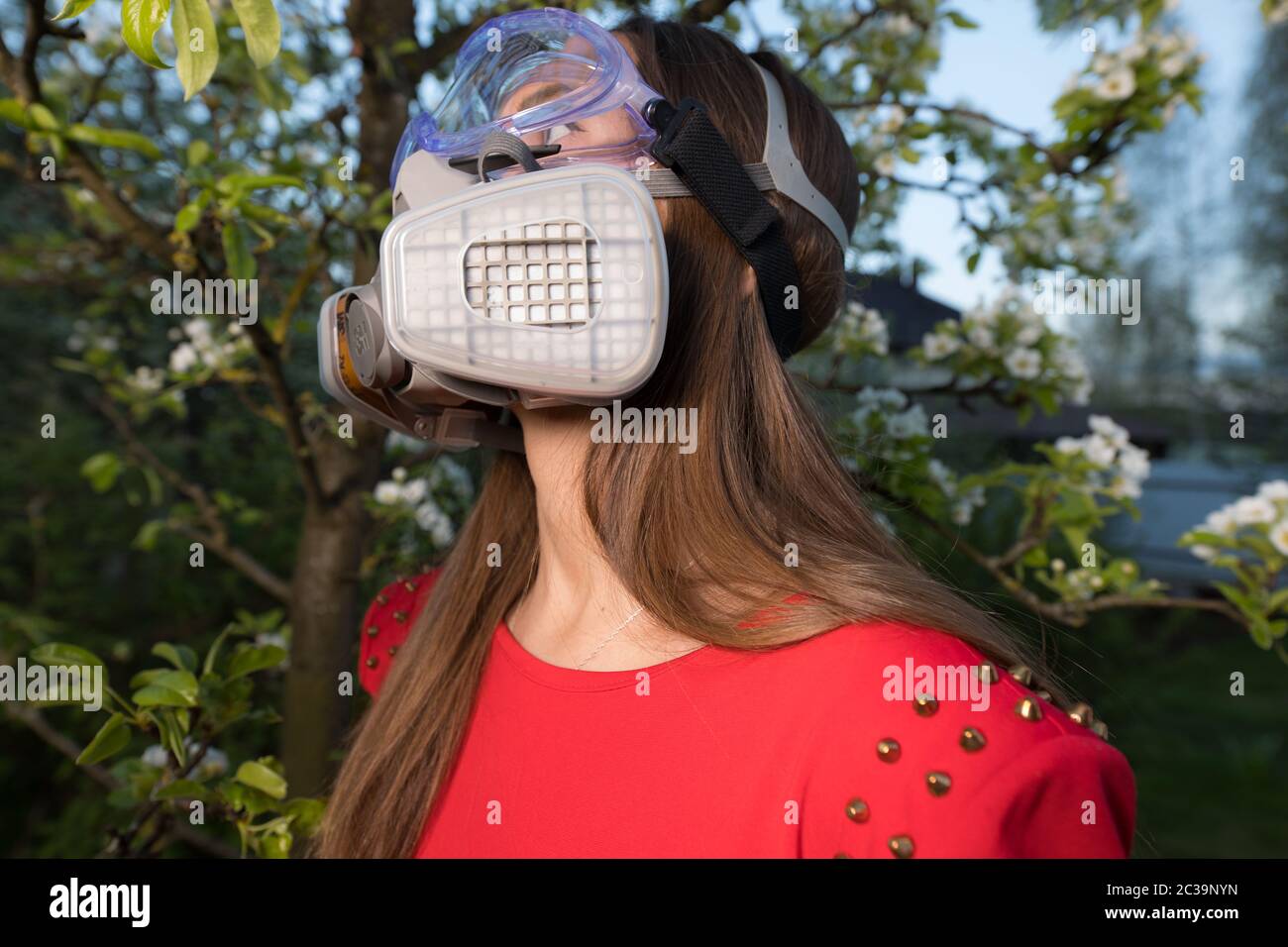 Jeune belle fille portrait dans un masque avec degré de protection 3M posant au crépuscule du jardin de printemps. Banque D'Images