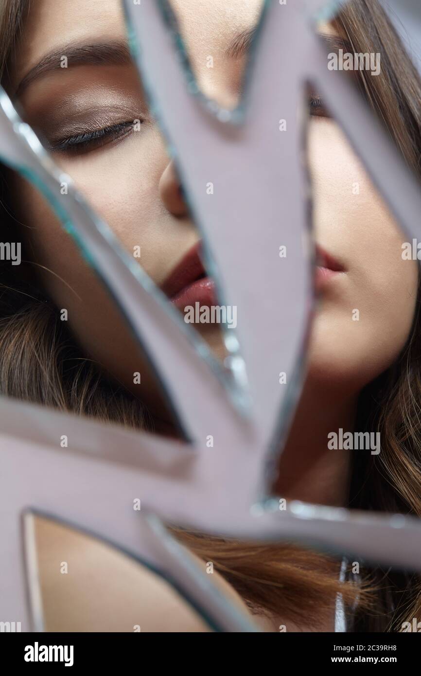 Jeune femme avec les yeux fermés dans le miroir. Portrait de la belle femme dans le miroir des éclats Banque D'Images