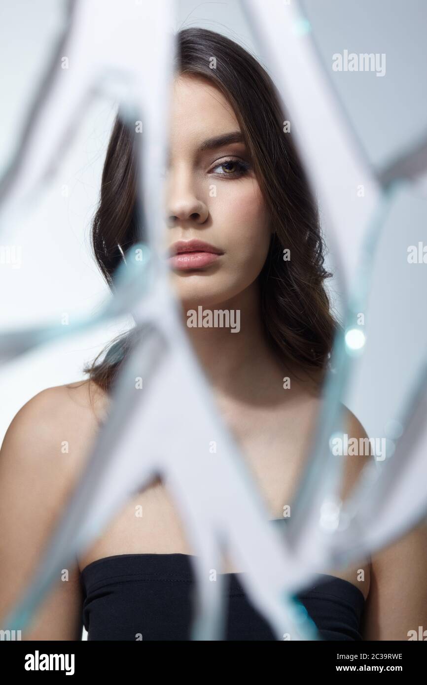 Une jeune femme regarde dans un miroir cassé. Portrait de la belle femme dans le miroir des éclats Banque D'Images