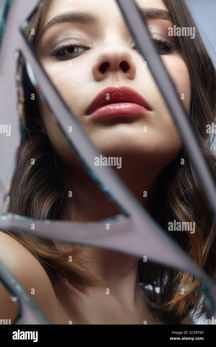 Une jeune femme regarde dans un miroir cassé. Portrait de la belle femme dans le miroir des éclats Banque D'Images