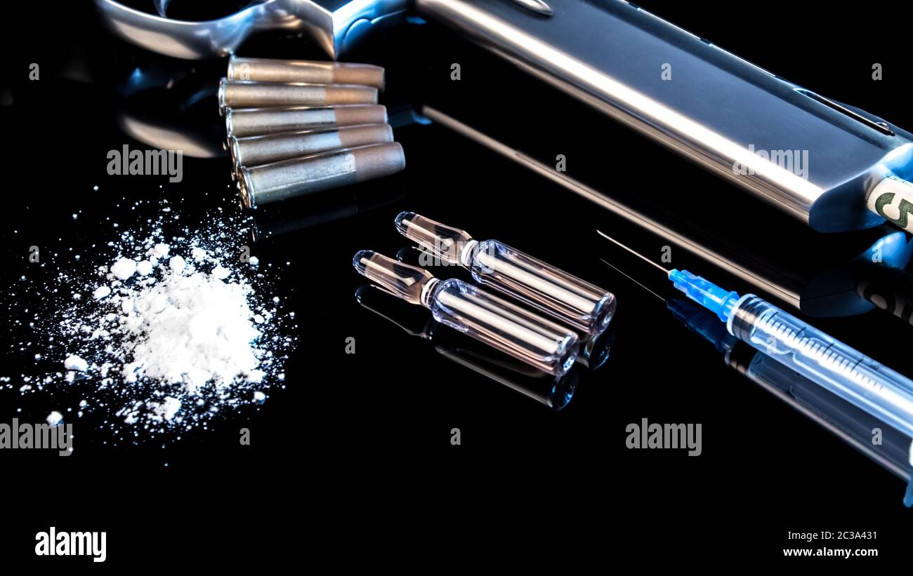 Une seringue avec une aiguille se trouve sur la table à côté de la drogue et les armes. La vente, la possession et la distribution de médicaments d'aujourd'hui. Mauvaises habitudes dangereuses, Banque D'Images