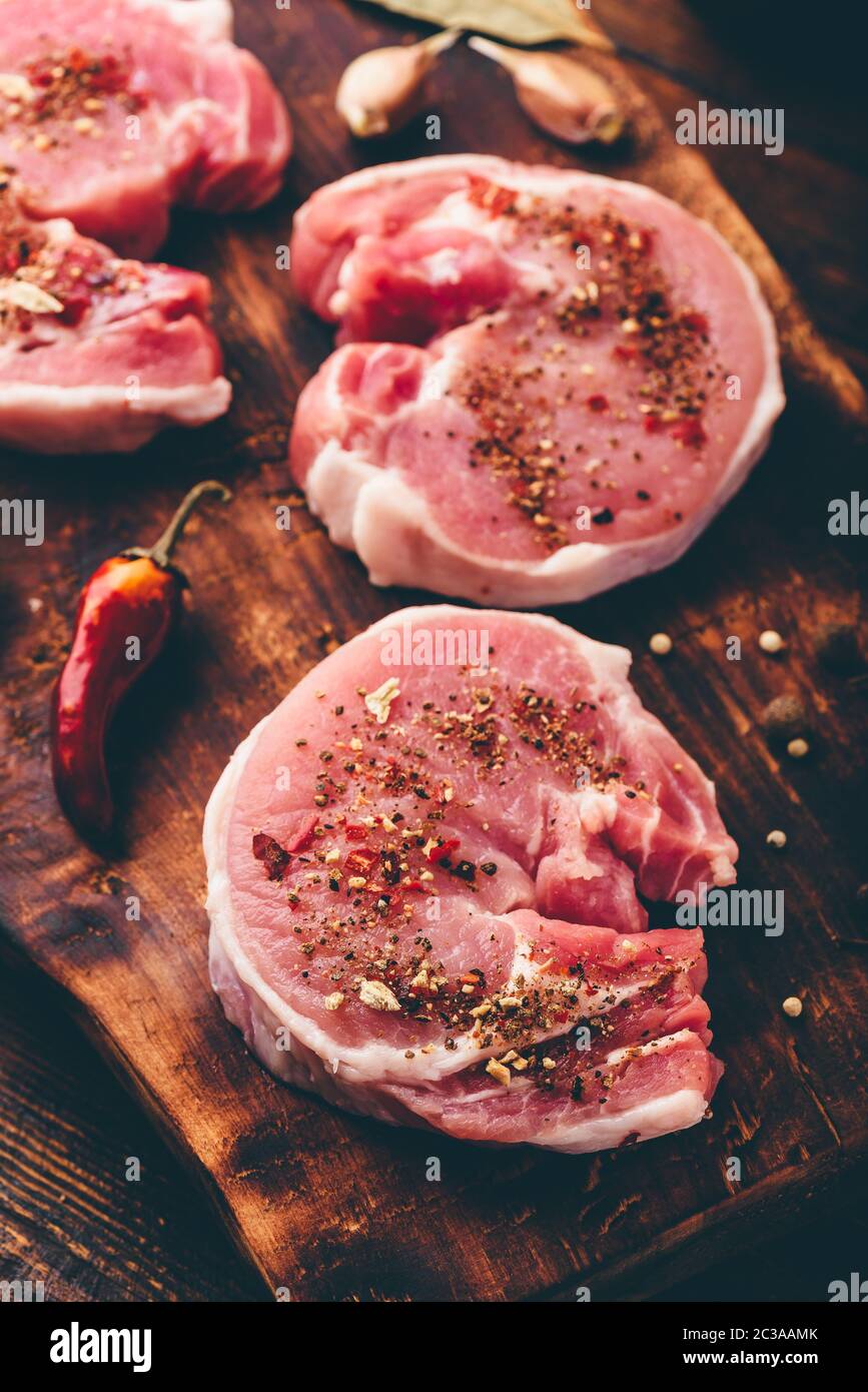 Steak de porc avec différentes épices sur planche à découper Banque D'Images