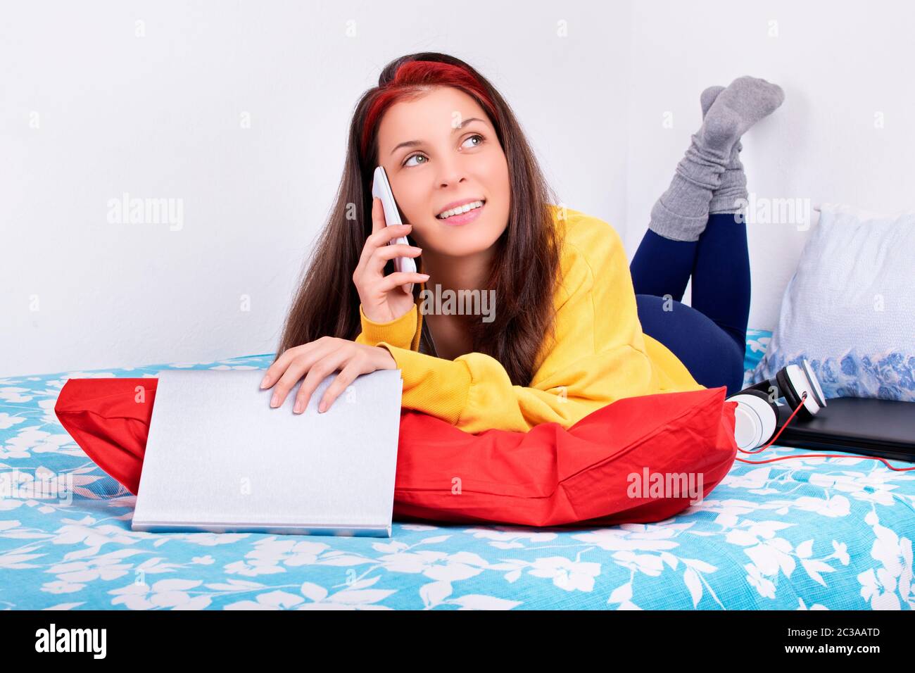 Communication, amitié concept. Belle jeune femme couché sur le lit dans sa chambre avec les pieds dans l'air parlant sur le téléphone portable. Jeune fille Banque D'Images