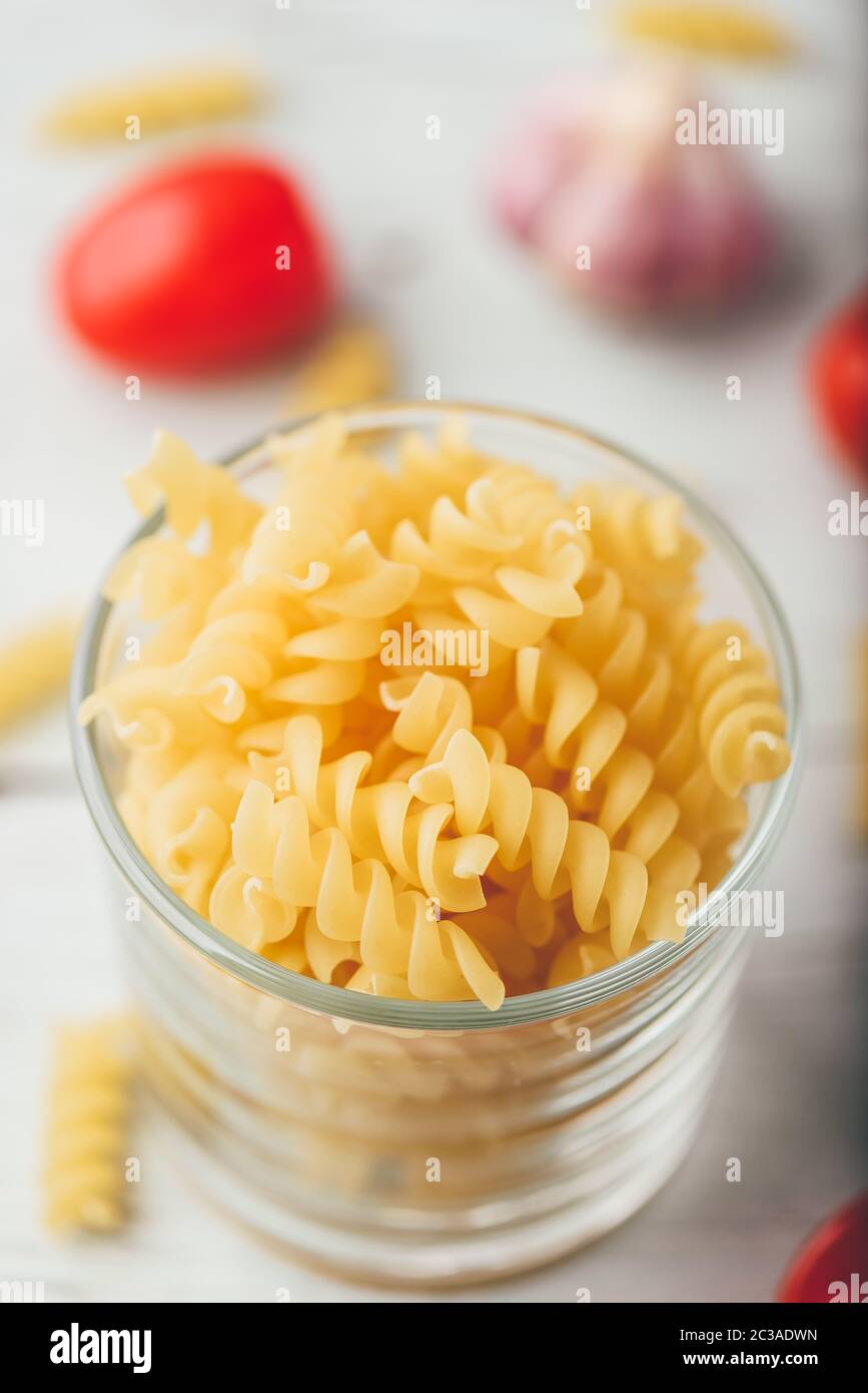 Fusillis italien dans bol en verre avec de l'ail et tomates cerises Banque D'Images