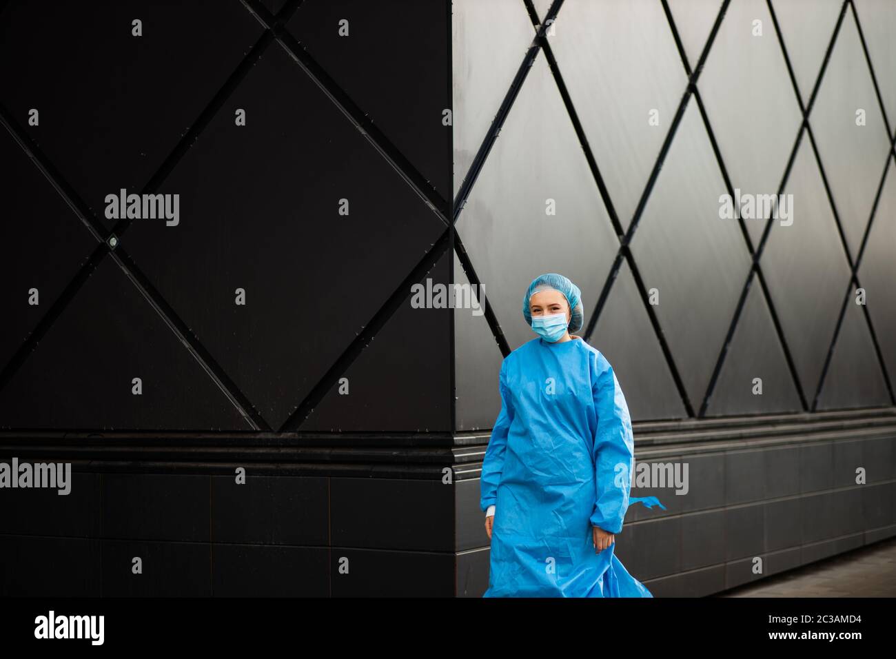 Femme médecin ou infirmière en masque médical et capuchon chirurgical bleu vous regardant Banque D'Images