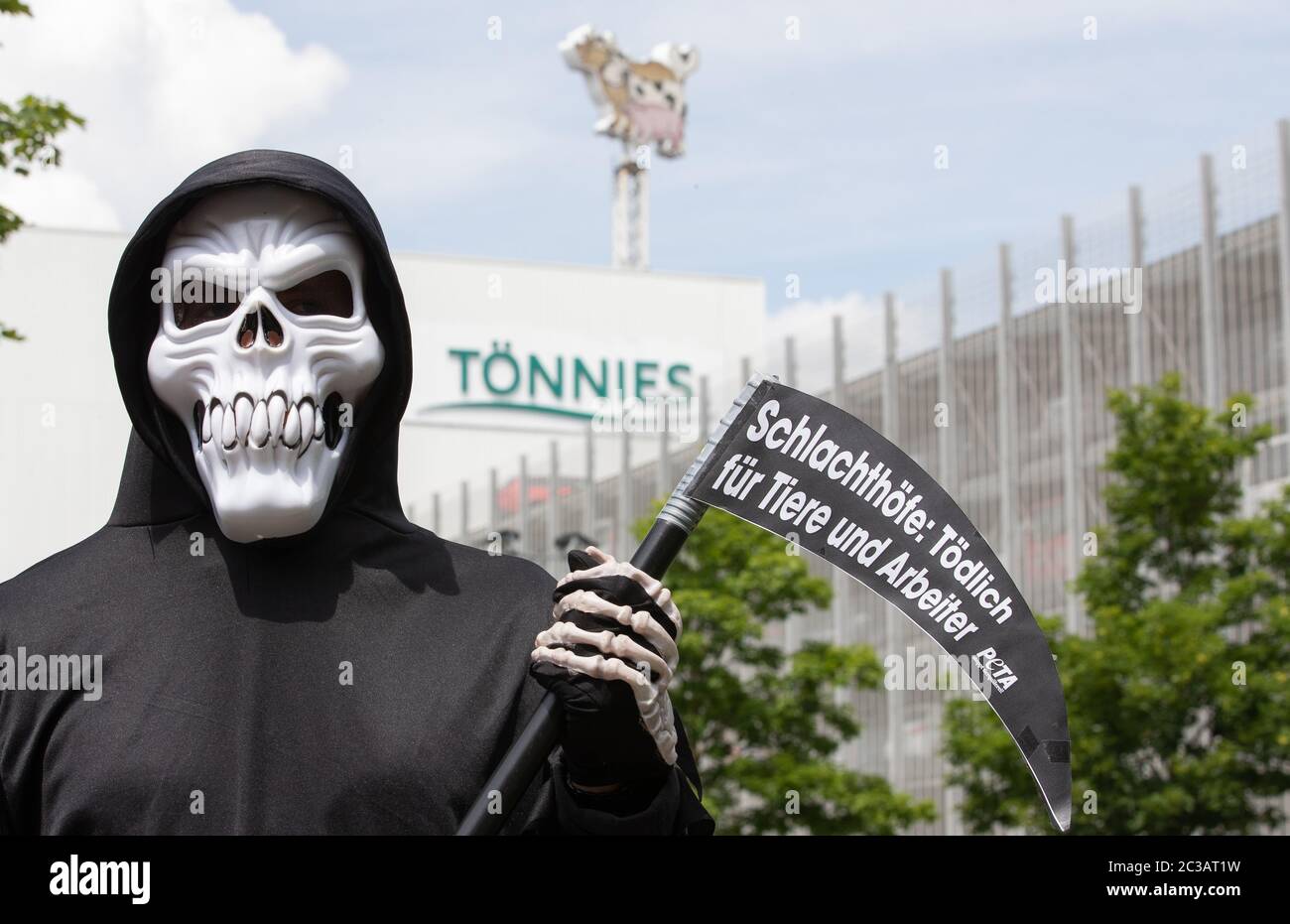 19 juin 2020, Rhénanie-du-Nord-Westphalie, Rheda-Wiedenbrück : un activiste de Peta, déguisé en mort, se dresse devant le logo Tönnies devant une salle de production. À l'abattoir de Tönnies à Rheda-Wiedenbrück, plusieurs centaines d'employés ont testé le virus corona depuis le début de la semaine. Photo: Friso Gentsch/dpa Banque D'Images