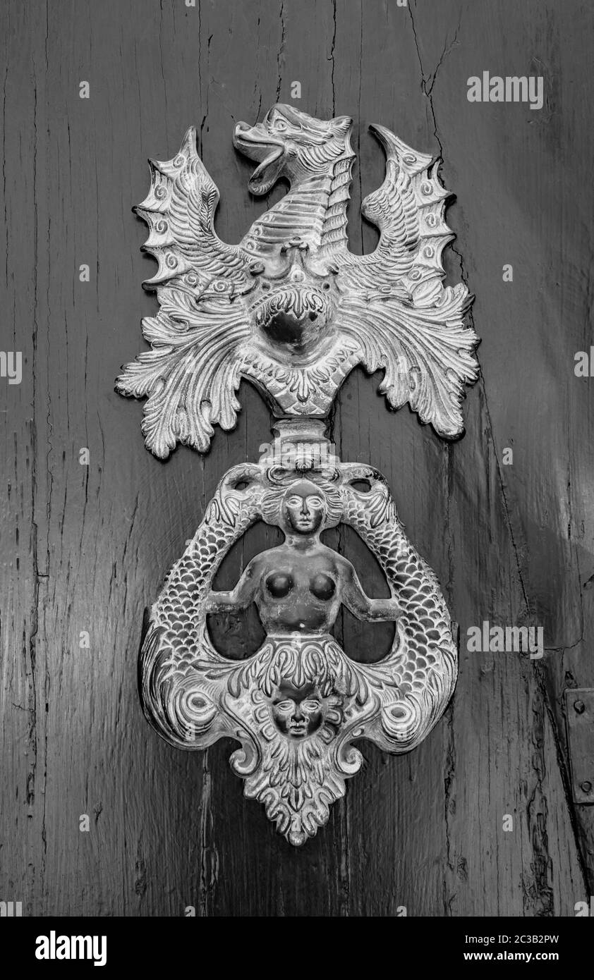 Un knocker en métal antique sur une porte en bois, qui représente un dragon et une sirène. Banque D'Images