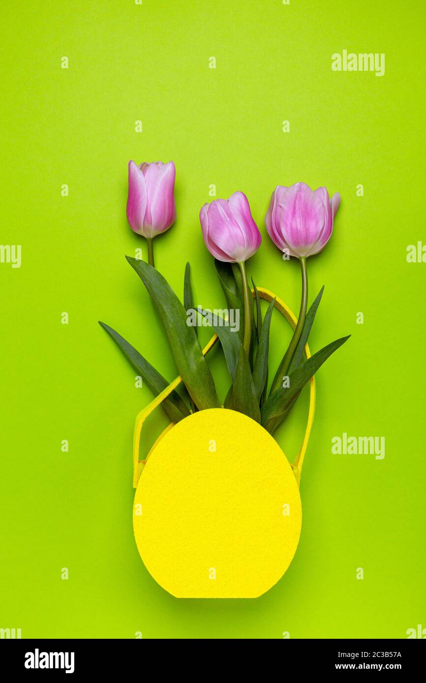 Tulipes roses dans un panier de Pâques jaune. Banque D'Images