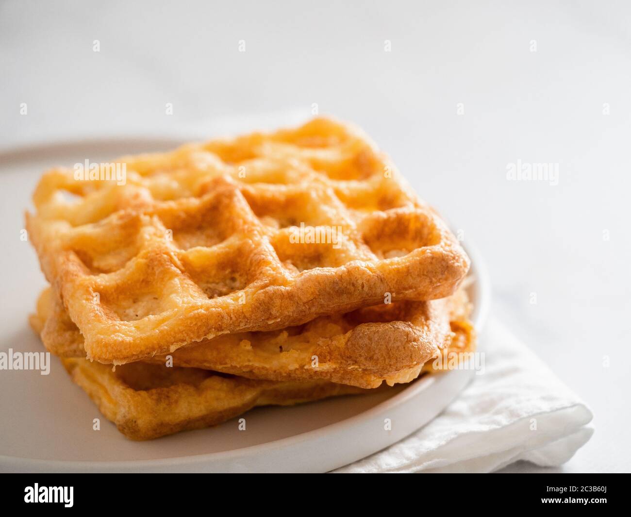 Gaufres salées parfait keto. Deux ingrédients chaffles sur plaque sur fond de marbre blanc. Les œufs et le fromage parmesan bas carb gaufres. Banque D'Images