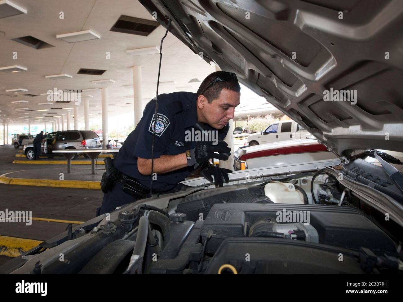 Laredo, Texas, États-Unis, 2012 : à un point de contrôle des douanes et de la protection des frontières des États-Unis, un agent inspecte de près un véhicule qui franchit la frontière entre le Mexique et les États-Unis à la recherche de drogues ou d'autres produits de contrebande éventuels. ©MKC / Daemmrich photos Banque D'Images