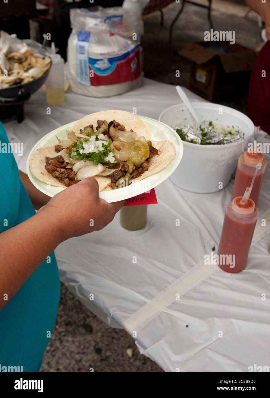 Austin, Texas Etats-Unis, 6 octobre 2012: Le patron tient une assiette de tacos de boeuf sur des tortillas de maïs avec l'oignon et la coriandre achetés au festival d'église. MKC / Daemmrich photos Banque D'Images