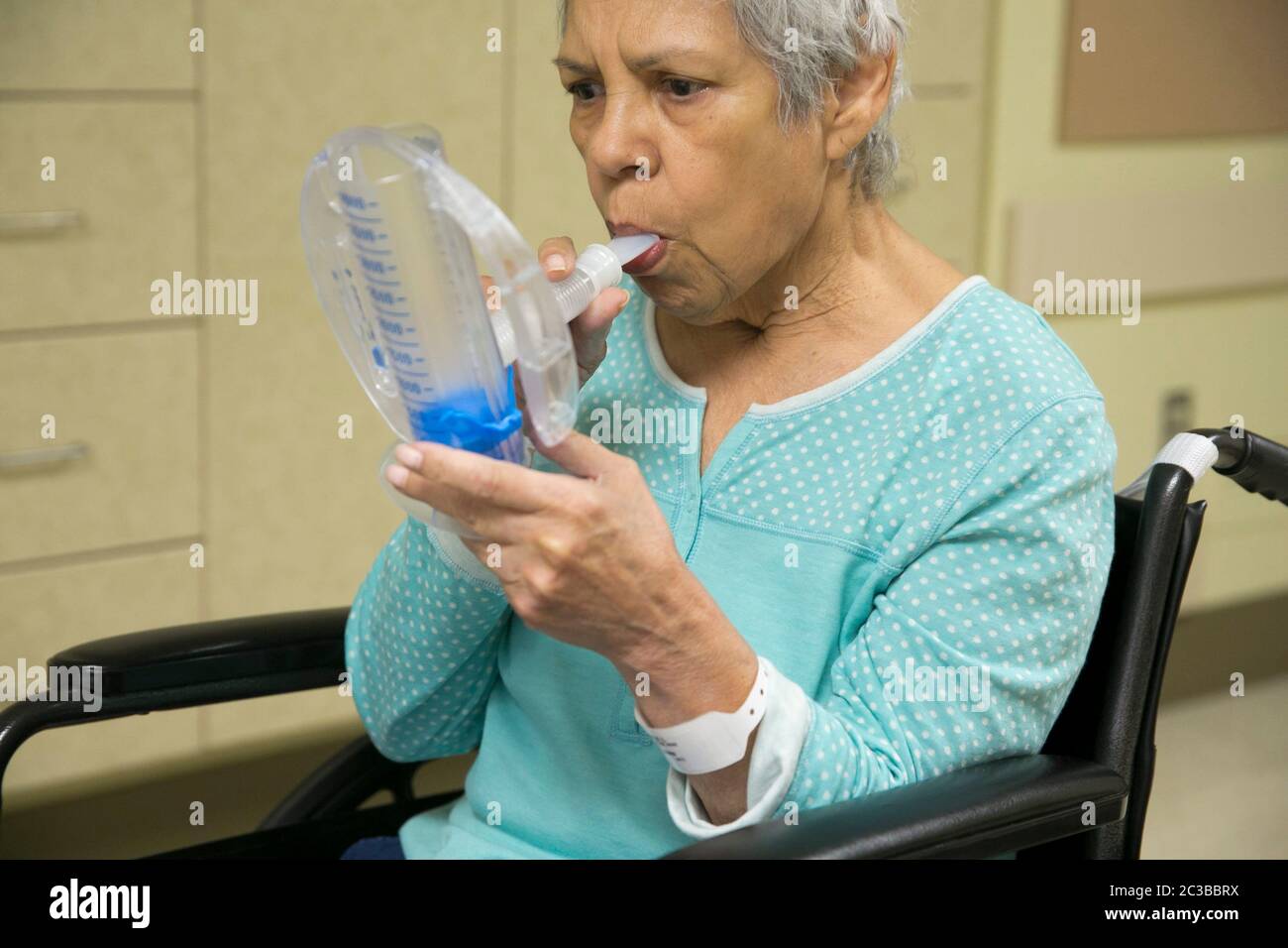 Austin Texas États-Unis, 11 février 2014: Une femme hispanique de 75 ans utilise un appareil médical d'exercice respiratoire tout en récupérant dans un hôpital de réadaptation. ©Marjorie Kamys Cotera/Daemmrich Photographie Banque D'Images