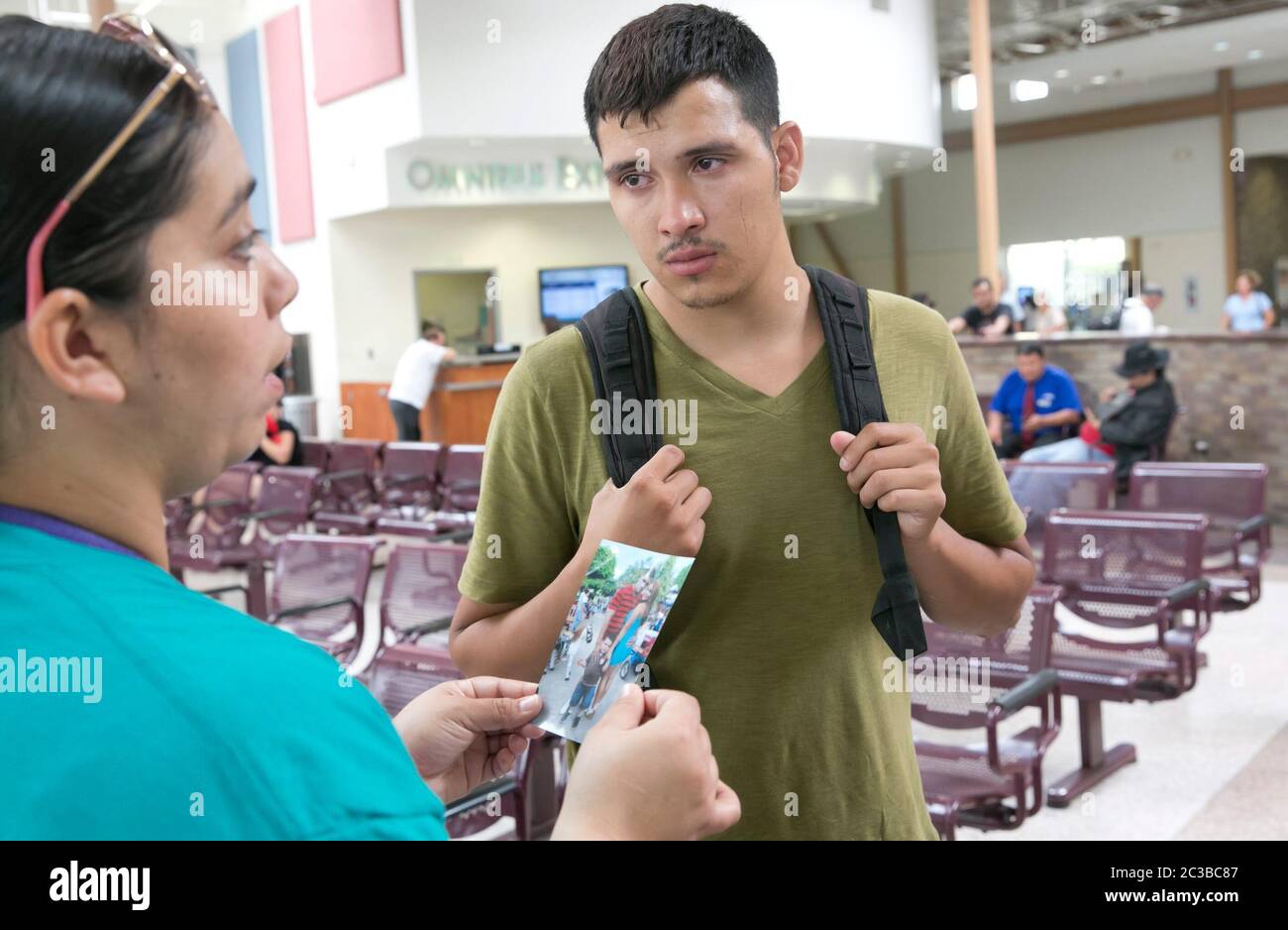 McAllen Texas USA, 24 juin 2014: JULIO Cesar Garcia Duarte, CITOYEN AMÉRICAIN, montre avec force une photo de sa famille lorsqu'il parle avec des bénévoles et des employés de la gare routière de McAllen, Texas, pour essayer d'obtenir des informations sur son épouse de fait guatémaltèque et son enfant qu'il tente de localiser. Il avait l'information qu'ils traversaient la frontière entre le Mexique et les États-Unis ce jour-là avec un « coyote ». ©Marjorie Kamys Cotera/Daemmrich Photographie Banque D'Images