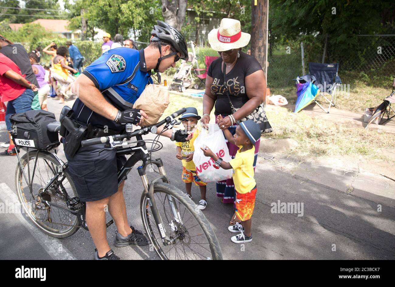 Dix-septième parade--Austin, Texas États-Unis, 21 juin 2014: L'officier de patrouille à vélo du département de police d'Austin interagit avec les jeunes enfants et leur grand-mère sur la route du dix-septième défilé annuel d'Austin à travers l'est d'Austin, dans le cadre d'une célébration d'une journée. Le dix-septième jour, également connu sous le nom de « Journée de la liberté » ou « Journée de l'émancipation », célèbre la fin de l'esclavage aux États-Unis à la fin de la guerre civile, ou la guerre entre les États. ©Marjorie Kamys Cotera/Daemmrich Photographie Banque D'Images