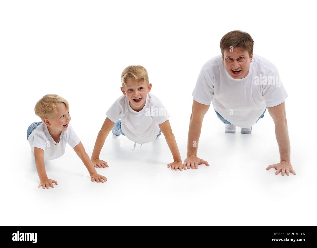 Père avec deux fils. Un jeune homme avec des enfants isolés sur un fond blanc fait des exercices de gymnastique. Pompes. Parentalité, concept de santé l Banque D'Images