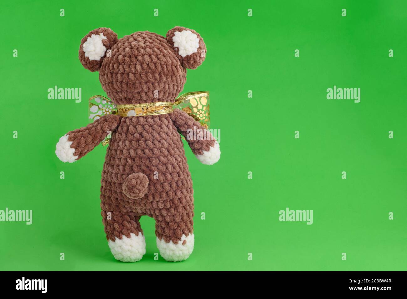 Ours en peluche tricoté pour enfants avec noeud sur fond vert Banque D'Images