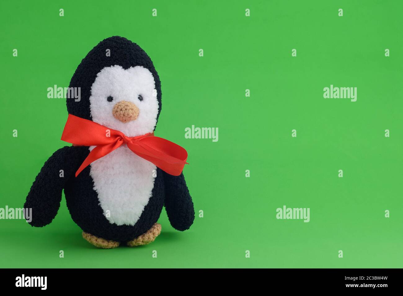 Pingouin en peluche tricoté sur fond vert Banque D'Images
