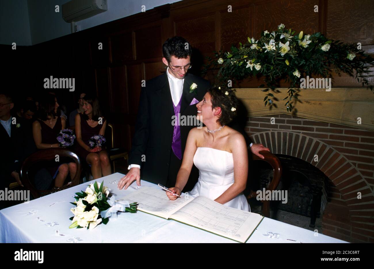 Mariée et marié dans leurs années vingt signant le registre à Wedding Banque D'Images