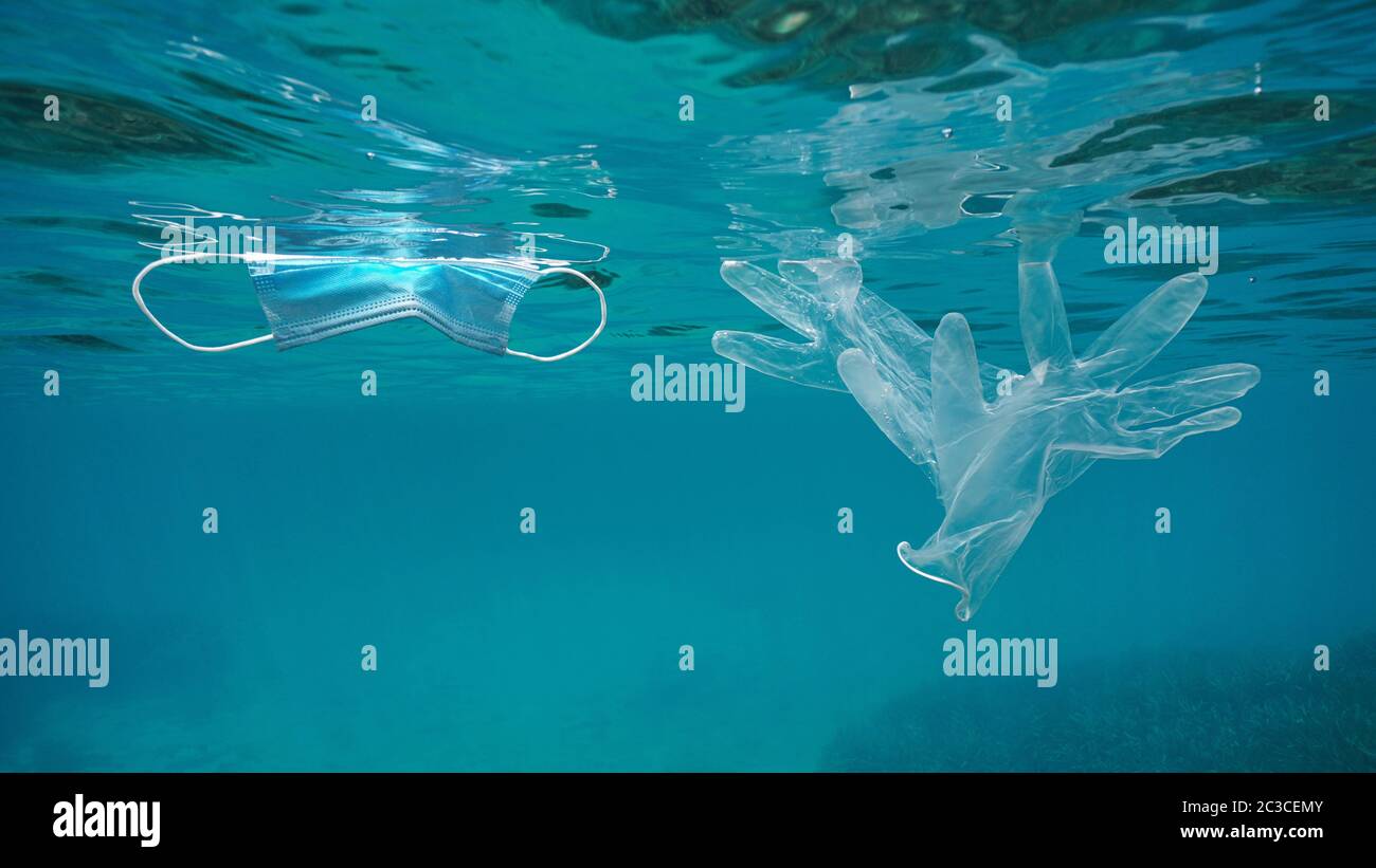 Masque facial et gants transparents sous l'eau, pollution des déchets plastiques dans la mer depuis la pandémie du coronavirus COVID-19 Banque D'Images