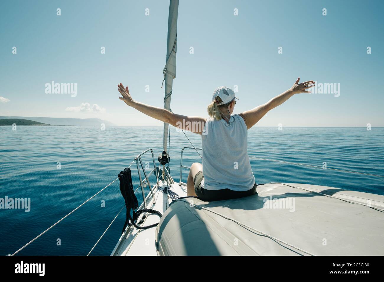 Femme assise sur les bateaux Bow appréciant le voyage en yacht avec les bras larges ouverts. Voile, navigation de plaisance et tr Banque D'Images