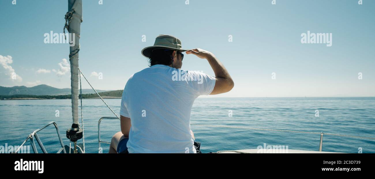 L'homme assis sur les navires s'aronde en profitant de la promenade en yacht. Concept de voile, de yachting et de voyage. Banque D'Images