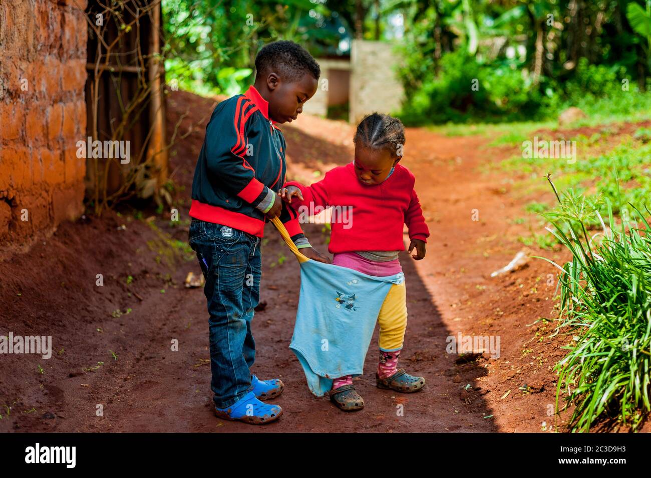 Bafoussam, cameroun - 20 août 2019 : un jeune garçon africain aide sa sœur à s'habiller, un exemple de soutien et de respect et de fraternité dans la famille Banque D'Images