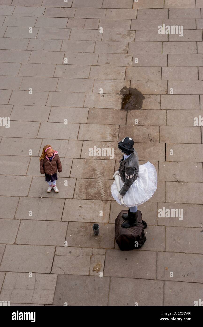 Une scène de rue avec une fille regardant un interprète de rue à Londres, Angleterre, Grande-Bretagne. Banque D'Images