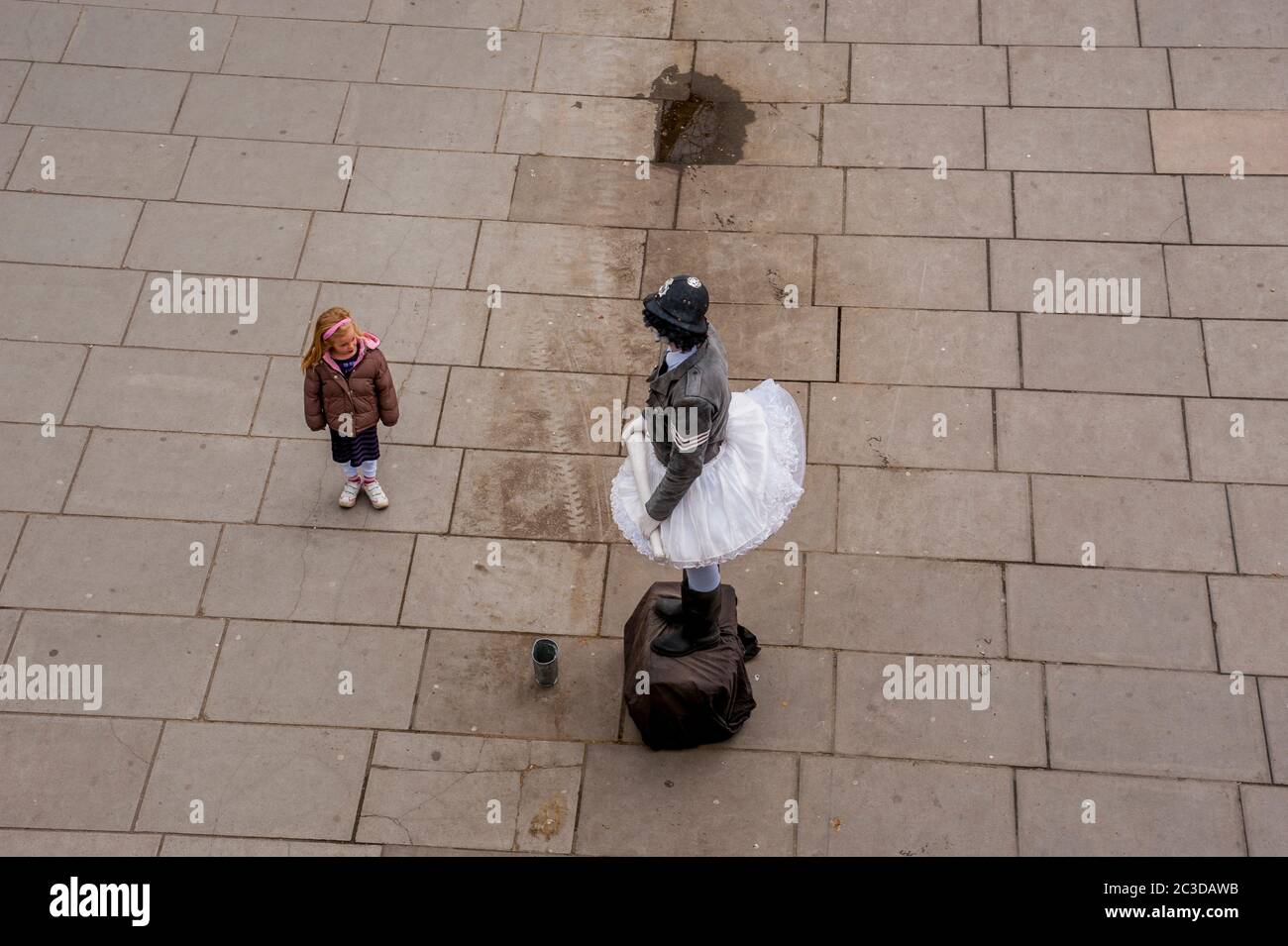 Une scène de rue avec une fille regardant un interprète de rue à Londres, Angleterre, Grande-Bretagne. Banque D'Images