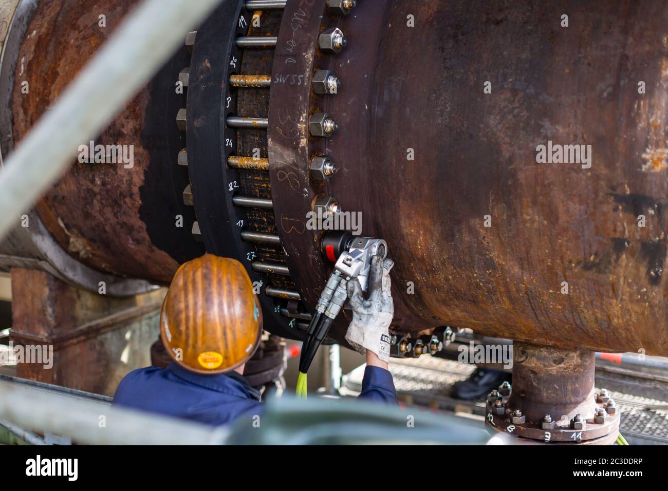 Un mécanicien avec équipement de protection individuelle, vu de l'arrière,  assemble un échangeur thermique avec le système de clé hydraulique HYTORC  Photo Stock - Alamy