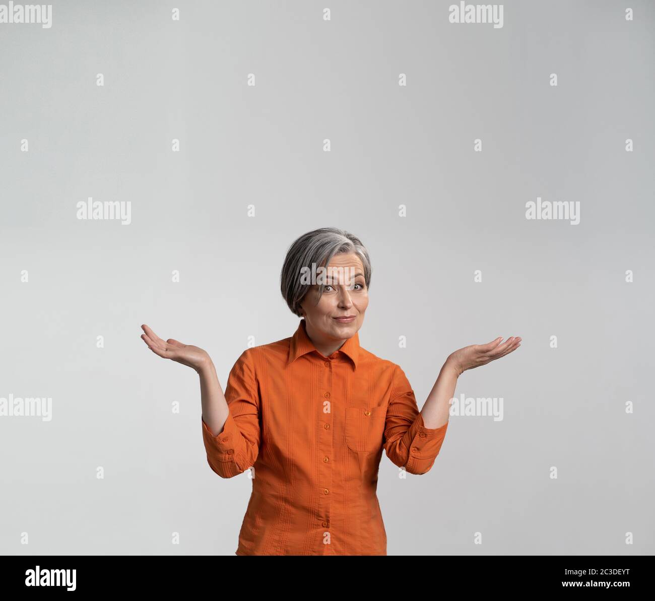 Surprise femme d'âge moyen présente un produit publicitaire souriant à la caméra avec des paumes ouvertes. Copier la flèche pour le texte. Gabarit carré pour publication sur Banque D'Images