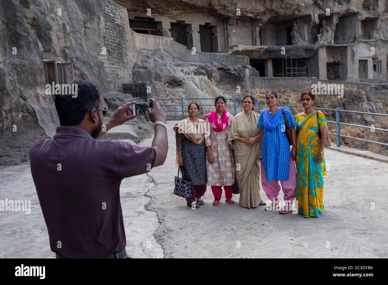 Homme prenant la photo de petites goupes de femmes devant les grottes d'Ellora, Aurangabad, Maharashtra, Inde. Banque D'Images
