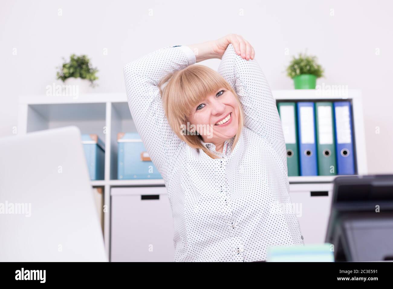 Femme d'affaires travaillant et étirant ses bras derrière la tête à l'intérieur au bureau à domicile. Travail, détente a Banque D'Images