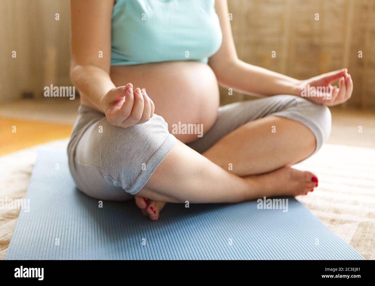 Jeune femme enceinte méditant en position de lotus Banque D'Images