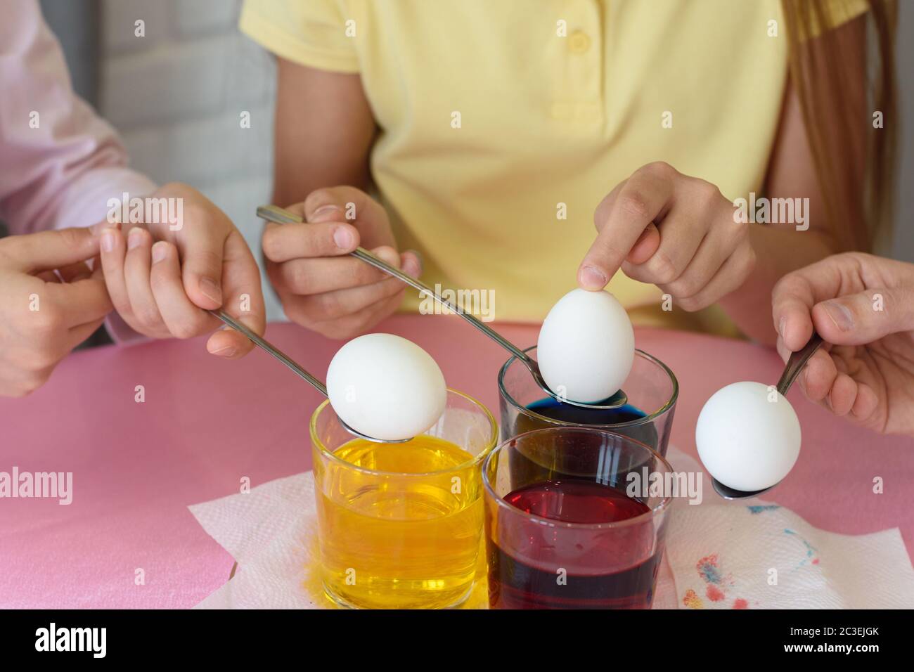 Les mains trempent les œufs de poulet dans une solution de colorant Banque D'Images
