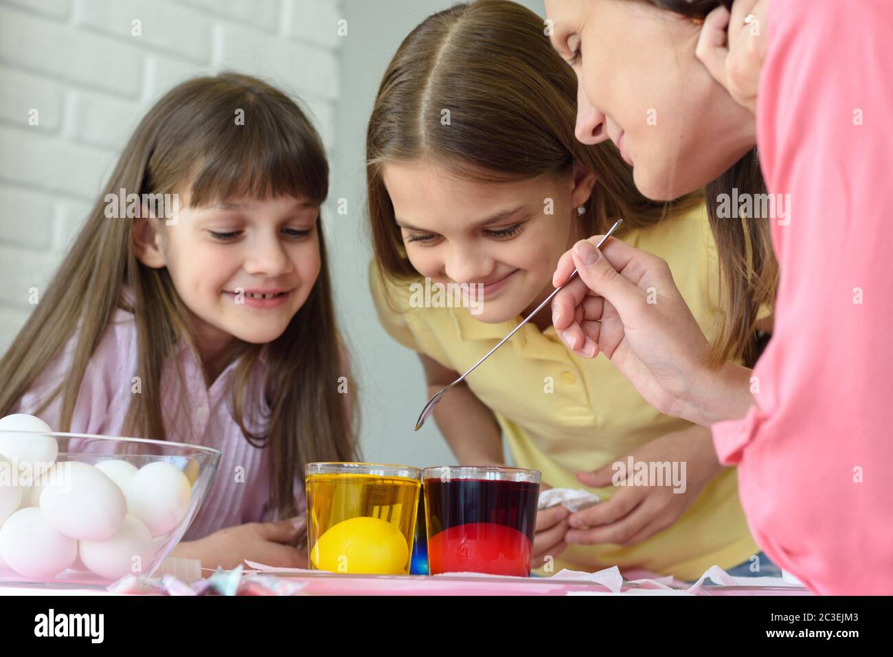 Plaisir en famille en regardant comment les œufs sont peints dans une solution avec des colorants Banque D'Images
