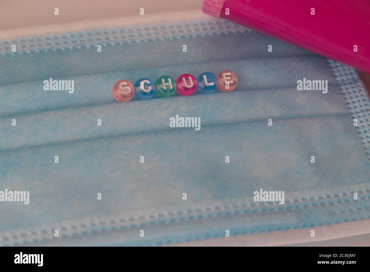 gros plan d'un masque avec le mot allemand Schule, signifie école, avec un cône rose dans le fond Banque D'Images