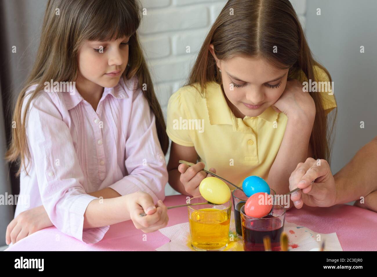 Les enfants tachent les œufs dans un colorant spécial dans les verres Banque D'Images