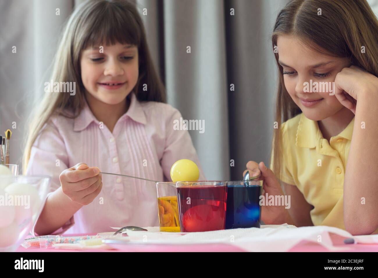 Les enfants peignent des œufs de Pâques dans des verres à colorant liquide Banque D'Images