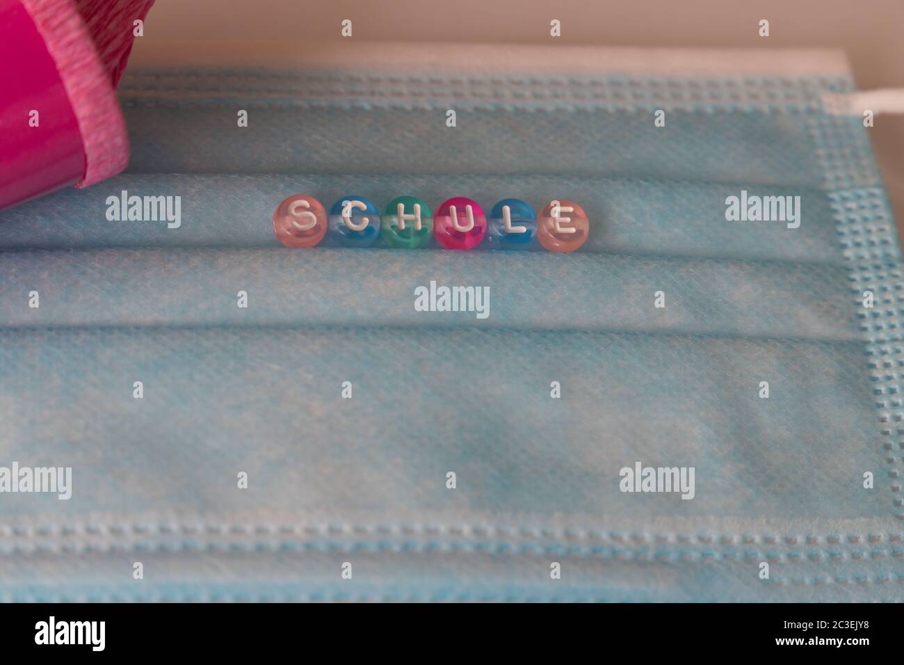 gros plan d'un masque avec le mot allemand Schule, signifie école, avec un cône rose dans le fond Banque D'Images