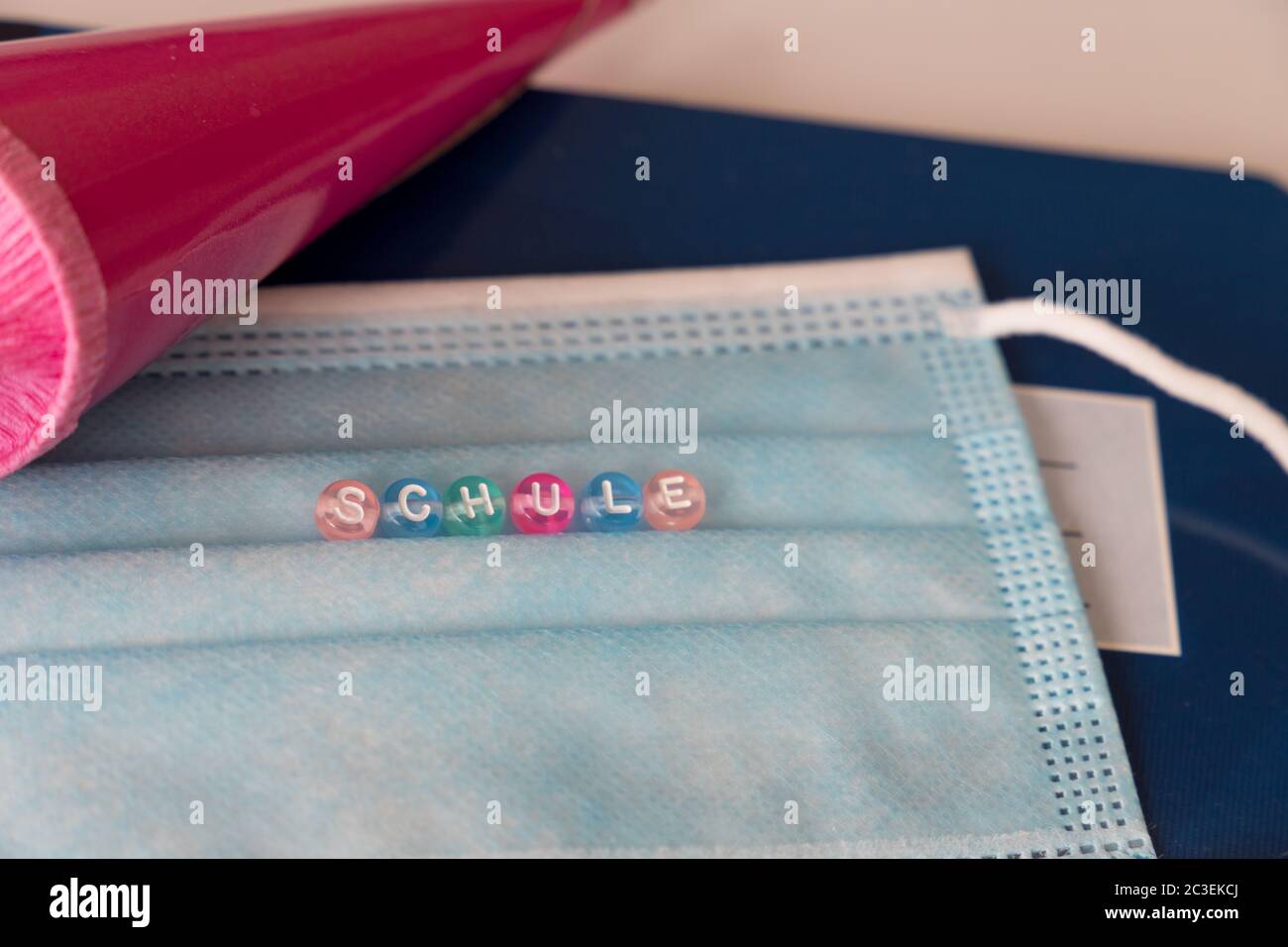 gros plan d'un masque avec le mot allemand Schule, signifie école, avec un cône rose dans le fond Banque D'Images
